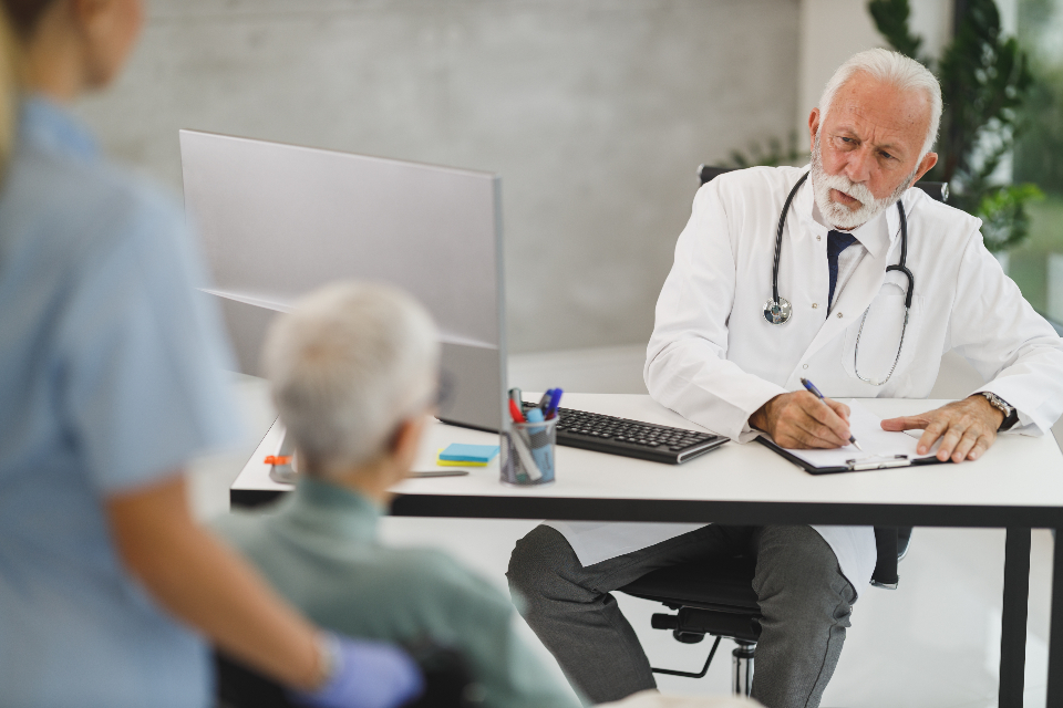 Doctor recording information at a consultation desk.